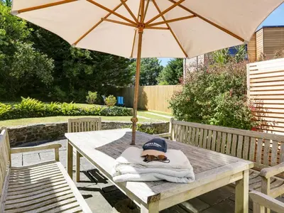 a picnic table with a dog laying on a towel under an umbrella at 4 Bed in Rock oc-r27255 in Saint Minver