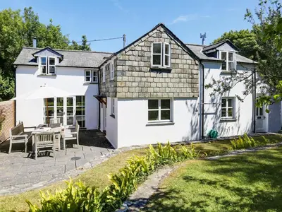 a white cottage with a table and chairs in a yard at 4 Bed in Rock oc-r27255 in Saint Minver