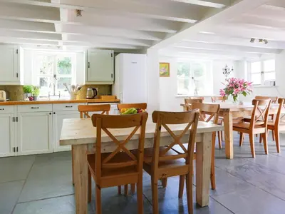 a kitchen and dining room with a wooden table and chairs at 4 Bed in Rock oc-r27255 in Saint Minver
