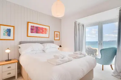 a bedroom with a white bed with a view of the ocean at 3 Bed in Port Isaac oc-secrft in Port Isaac