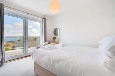 a bedroom with a large white bed and a large window at 3 Bed in Port Isaac oc-secrft in Port Isaac