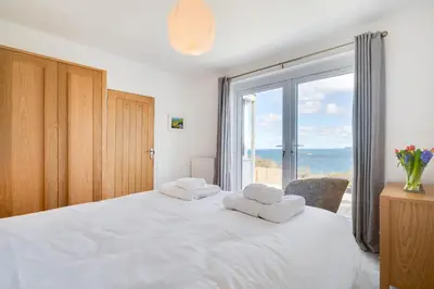 a bedroom with a white bed with a large window at 3 Bed in Port Isaac oc-secrft in Port Isaac