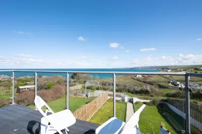 a balcony with two white chairs and the ocean at 3 Bed in Port Isaac oc-secrft in Port Isaac