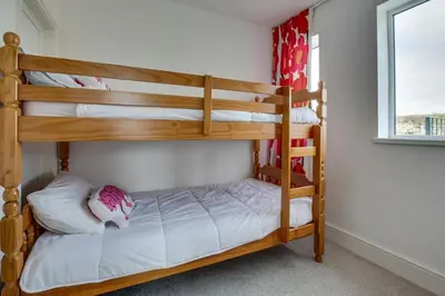 two bunk beds in a room with a window at 5 Bed in Praa Sands oc-seacro in Praa Sands