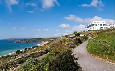 a building on top of a hill next to the ocean at 5 Bed in Praa Sands oc-seacro in Praa Sands