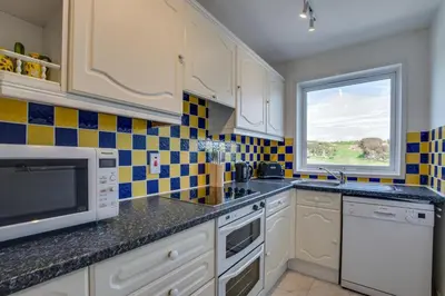 a kitchen with white cabinets and a window at 5 Bed in Praa Sands oc-seacro in Praa Sands