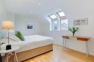 a white bedroom with a bed and a table at 3 Bed in Trevone oc-stcad in Padstow