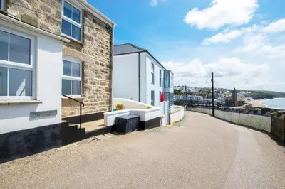 a brick building with a pathway next to the ocean at 2 Bed in Porthleven oc-stmich in Porthleven