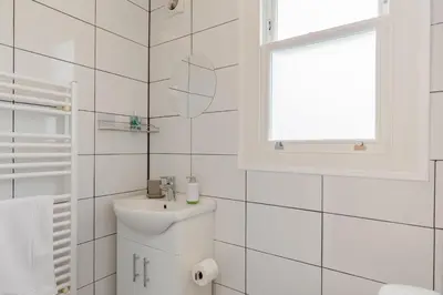 a white bathroom with a sink and a window at 1 Bed in Looe oc-terry in Looe