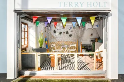 a store front with colorful flags and a table at 1 Bed in Looe oc-terry in Looe