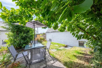 a table and chairs with an umbrella in a yard at 2 Bed in St. Teath oc-shilli in Saint Teath