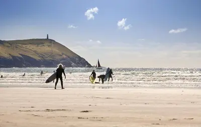 a group of people walking on the beach with surfboards at 2 Bed in St. Teath oc-shilli in Saint Teath
