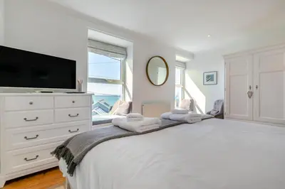 a white bedroom with a large bed and a tv at 2 Bed in Porthleven oc-suffol in Porthleven