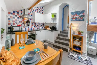 a kitchen with a wooden table and a kitchen with a staircase at 1 Bed in Porthleven oc-smuggl in Porthleven