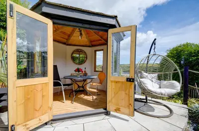 a tiny house with a patio with a table and a swing at 3 Bed in Fowey oc-tidewa in Fowey
