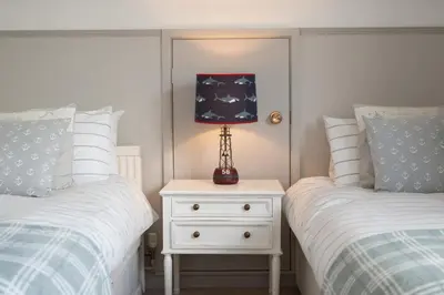 a bedroom with two beds and a night stand with a lamp at 3 Bed in Fowey oc-tidewa in Fowey