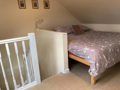 a small bedroom with a bed and a staircase at 'Anchor Point', Porthtowan in Porthtowan