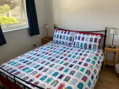 a bed with a colorful comforter and pillows at 'Anchor Point', Porthtowan in Porthtowan