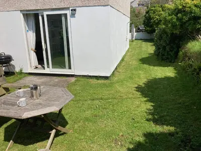 a backyard with a table and a grill in the grass at 'Anchor Point', Porthtowan in Porthtowan