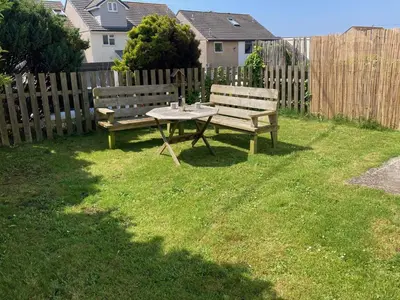 two benches sitting next to a table in a yard at 'Anchor Point', Porthtowan in Porthtowan
