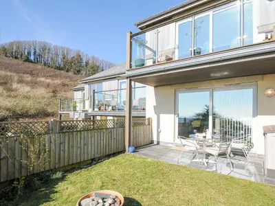 a house with a patio with a table and chairs at Pebbles in Torpoint