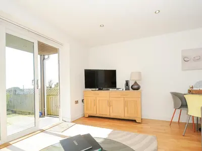 a living room with a flat screen tv on a wooden cabinet at Pebbles in Torpoint