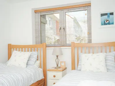 two beds in a bedroom with a window at Pebbles in Torpoint