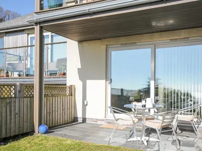 a patio with a table and chairs on a balcony at Pebbles in Torpoint