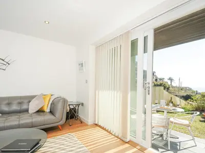 a living room with a couch and a balcony at Pebbles in Torpoint