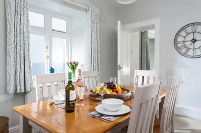 a dining room with a wooden table with a bowl of fruit at Nimbus Cottage in St Merryn