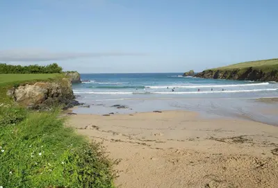 a beach with people surfing in the ocean at Nimbus Cottage in St Merryn