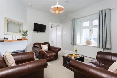 a living room with leather furniture and a window at Nimbus Cottage in St Merryn