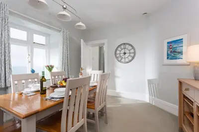 a dining room with a table and chairs and a clock at Nimbus Cottage in St Merryn