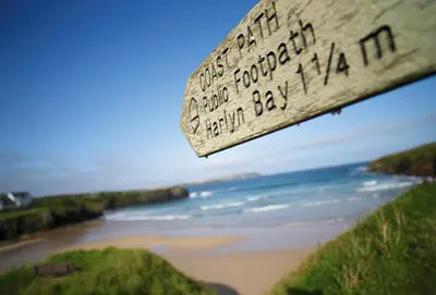 a view of a beach with a wooden sign at Owl House in Wadebridge