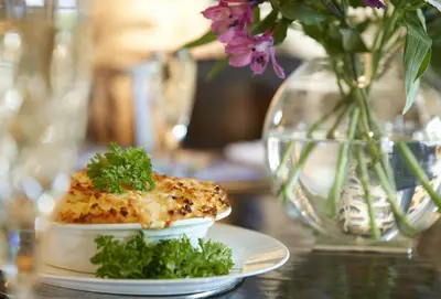 a plate of food on a table with a vase with flowers at Tregadjack Barn in Crowan