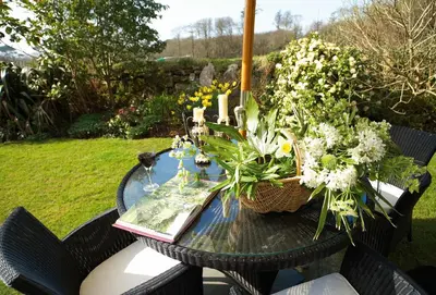 a table with a book and flowers on it at Tregadjack Barn in Crowan