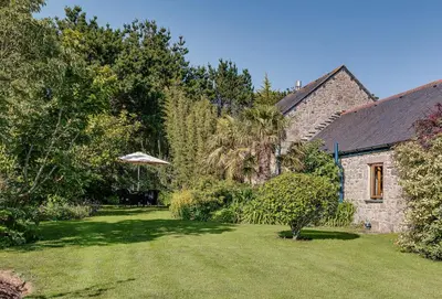 a yard with a stone house with a lawn at Tregadjack Barn in Crowan
