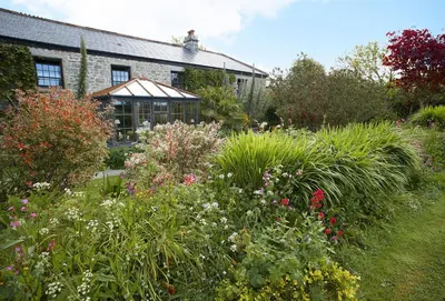 a garden with flowers in front of a house at Tregadjack Farmhouse in Crowan