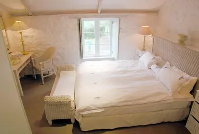 a bedroom with a large white bed with a window at Bonython Farmhouse in Helston