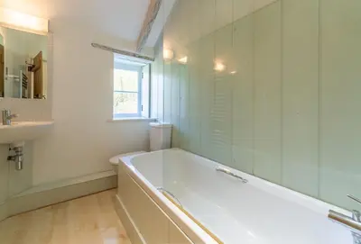 a white bathroom with a tub and a sink at Bonython Farmhouse in Helston