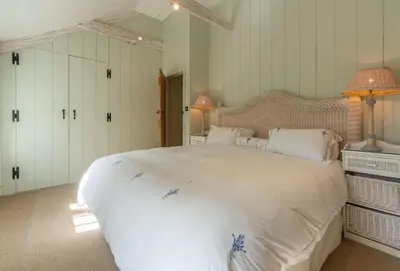 a bedroom with a large white bed with two lamps at Bonython Farmhouse in Helston
