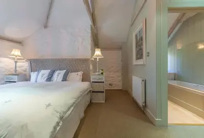 a bedroom with a large bed and a bath tub at Bonython Farmhouse in Helston