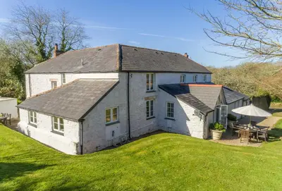 a large white house with a grass yard at Bonython Farmhouse in Helston