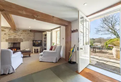 a living room with a door open to a patio at Bonython Farmhouse in Helston