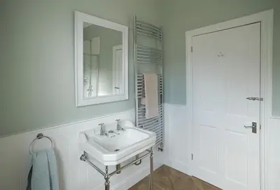 a white bathroom with a sink and a mirror at Rosevean House in St. Agnes