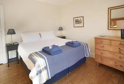 a bedroom with a bed with two blue towels on it at Rosevean House in St. Agnes