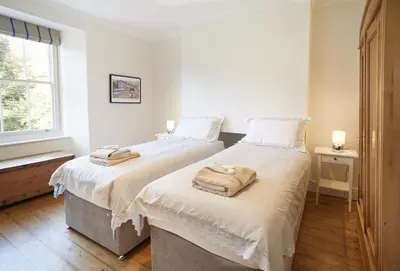 two twin beds in a room with a window at Rosevean House in St. Agnes