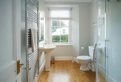 a bathroom with a toilet and a sink and a window at Rosevean House in St. Agnes