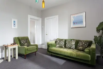 a living room with two green chairs and a couch at Pelorus Cottage in St Merryn