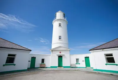 a white lighthouse sitting on top of a building at Pelorus Cottage in St Merryn